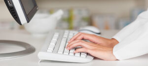 racorn130705324.jpg - closeup of pharmacist's hands typing on computer keyboard at pharmacy counter