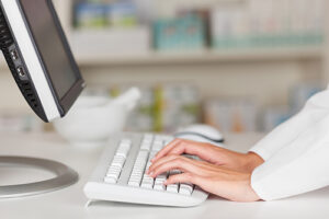 racorn130705324.jpg - closeup of pharmacist's hands typing on computer keyboard at pharmacy counter